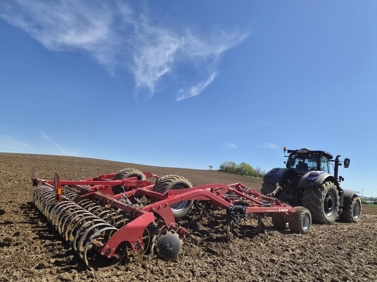 NM- Nerchau-Mutzschener - Landwirtschaft - Eine rote HORSCH Joker RT Scheibenegge arbeitet auf einem braunen, gepflügten Acker unter strahlend blauem Himmel.